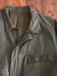 Taupe leather jacket with a collar and pocket on a wooden surface