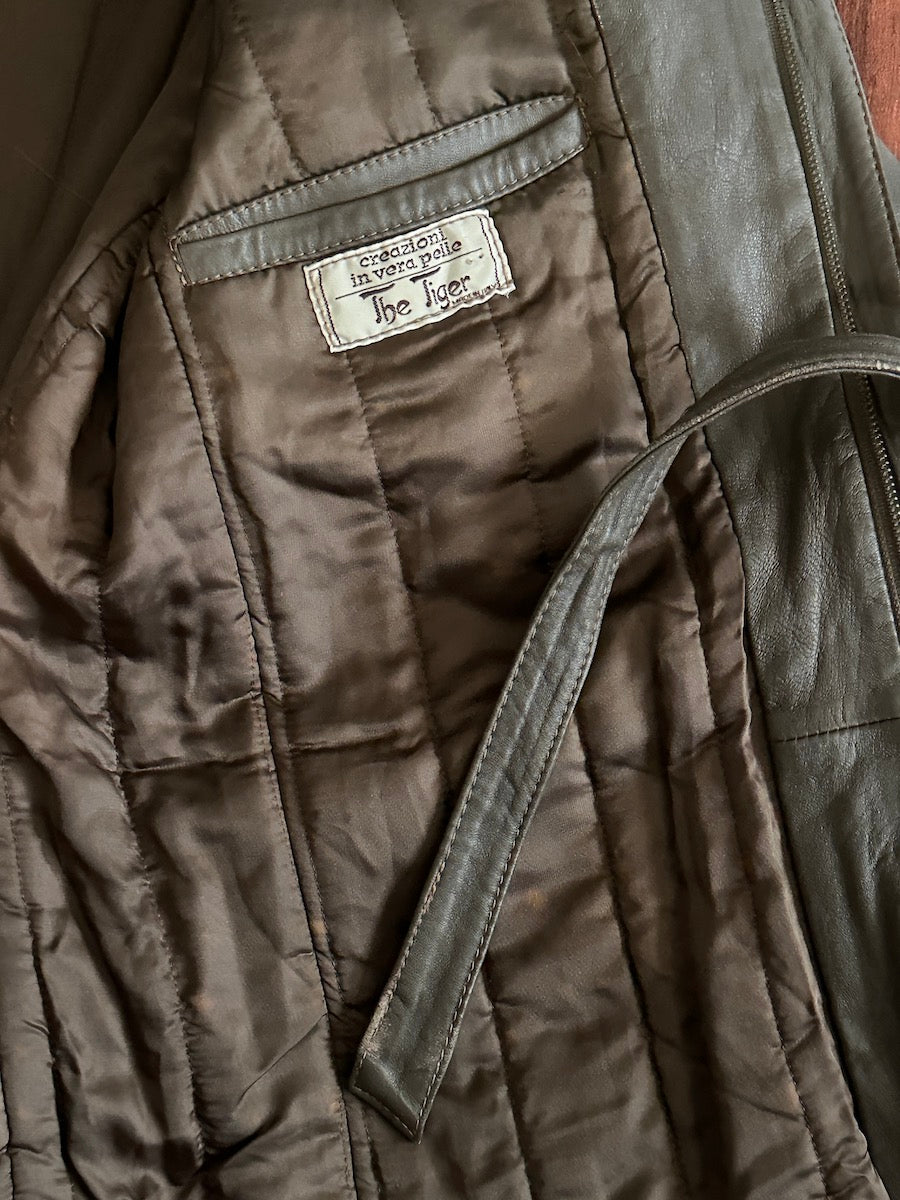 Close-up of the inside of a taupe quilted lining of a leather jacket with a brand label on the inner chest pocket.