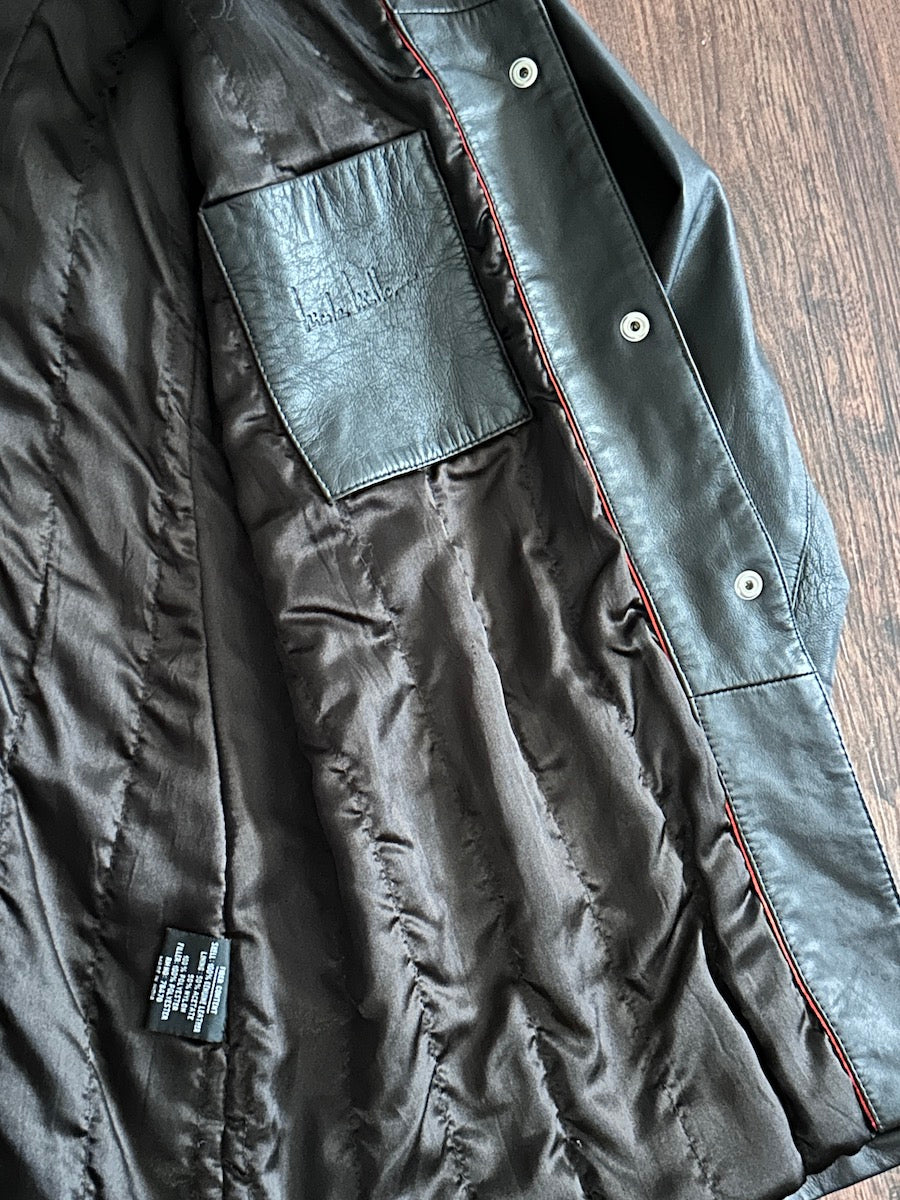 Inside of a chocolate brown jacket with leather inner chest patch pocket on a wooden surface