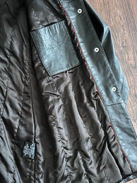Inside of a chocolate brown jacket with leather inner chest patch pocket on a wooden surface