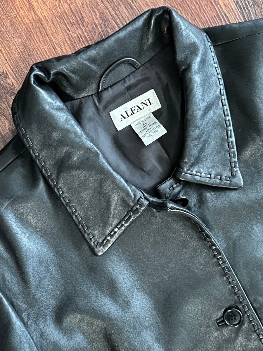 Close-up of a black leather jacket with a visible brand label on a wooden surface
