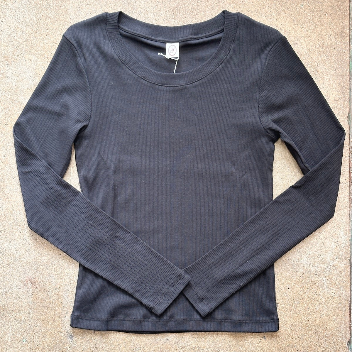 Black ribbed long-sleeve shirt on a beige surface