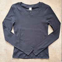 Black ribbed long-sleeve shirt on a beige surface