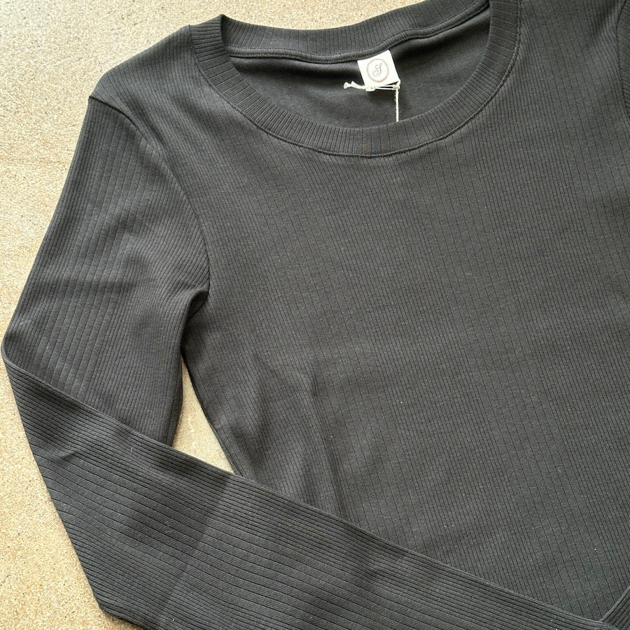Black ribbed cotton long-sleeve shirt on a beige surface