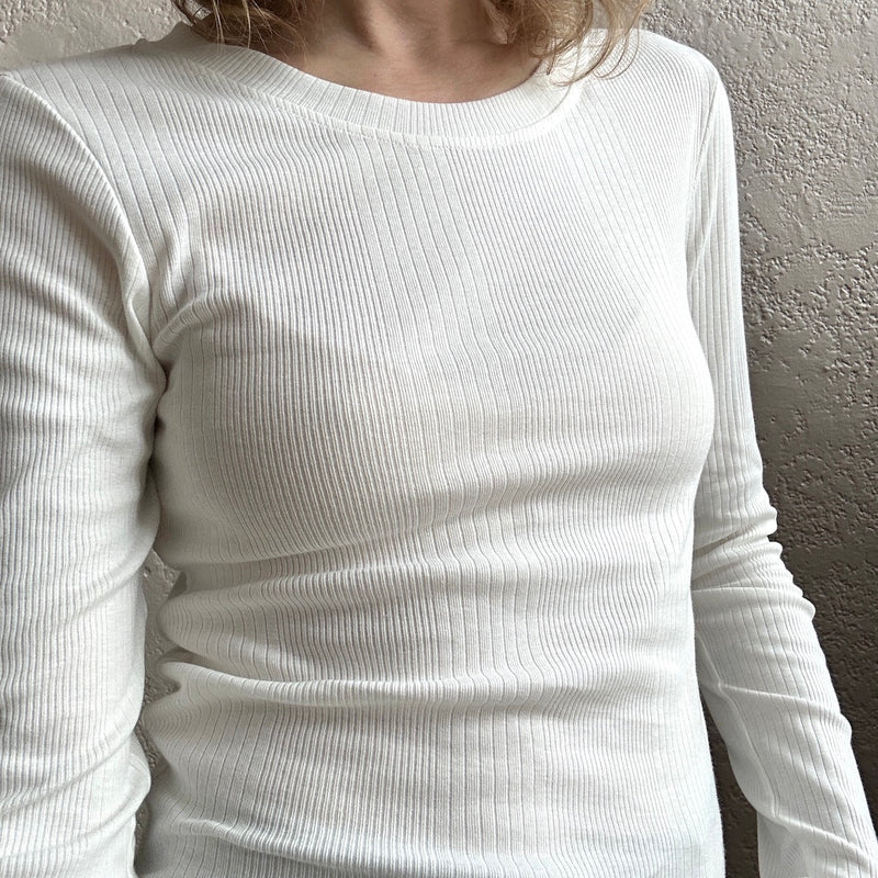 White ribbed long-sleeve shirt worn by a person against a neutral background