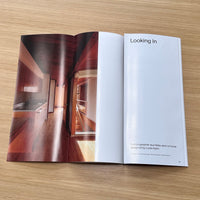 Open book showing interior design images and text on a wooden surface