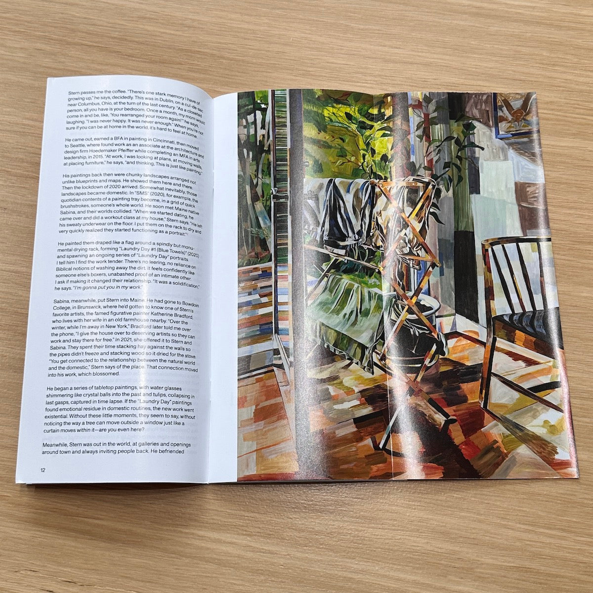 Open book with a painting on one page and text on the other, on a wooden surface.