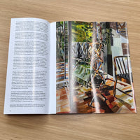 Open book with a painting on one page and text on the other, on a wooden surface.