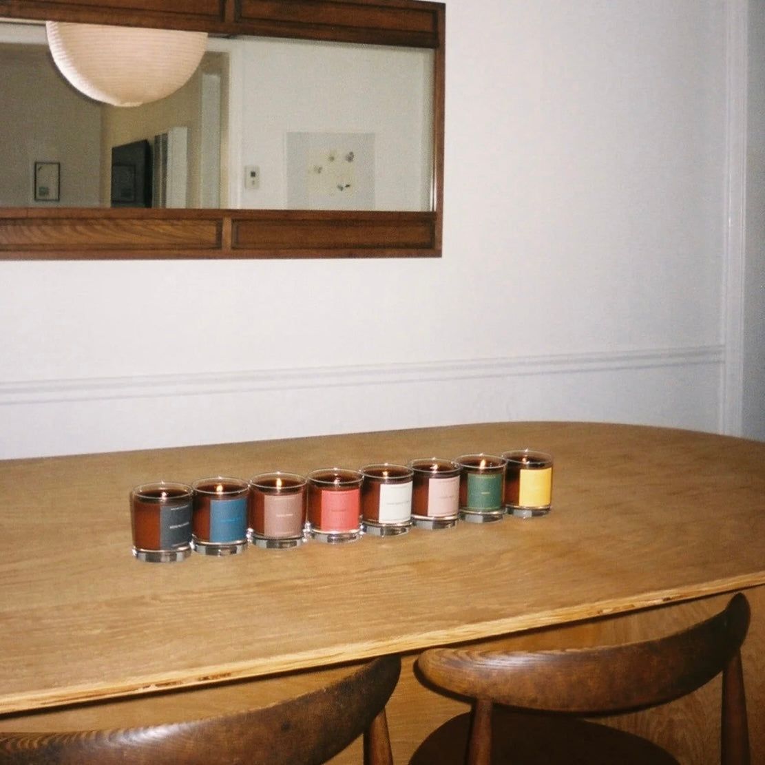 Row of candles on a wooden table with a mirror above