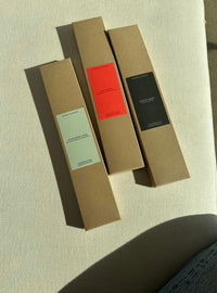 Three cardboard boxes of incense with different colored labels on a textured surface