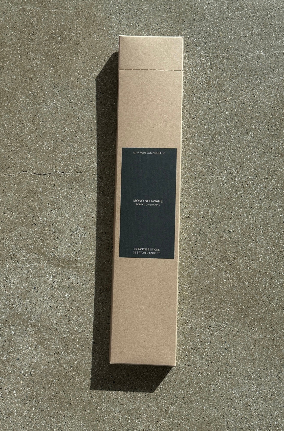Cardboard box of incense sticks with a black label on a concrete surface