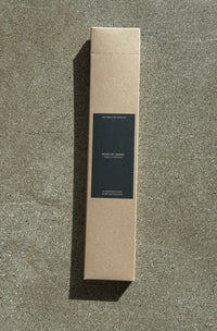 Cardboard box of incense sticks with a black label on a concrete surface