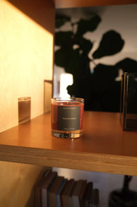 Candle in a glass holder on a wooden shelf with a blurred background