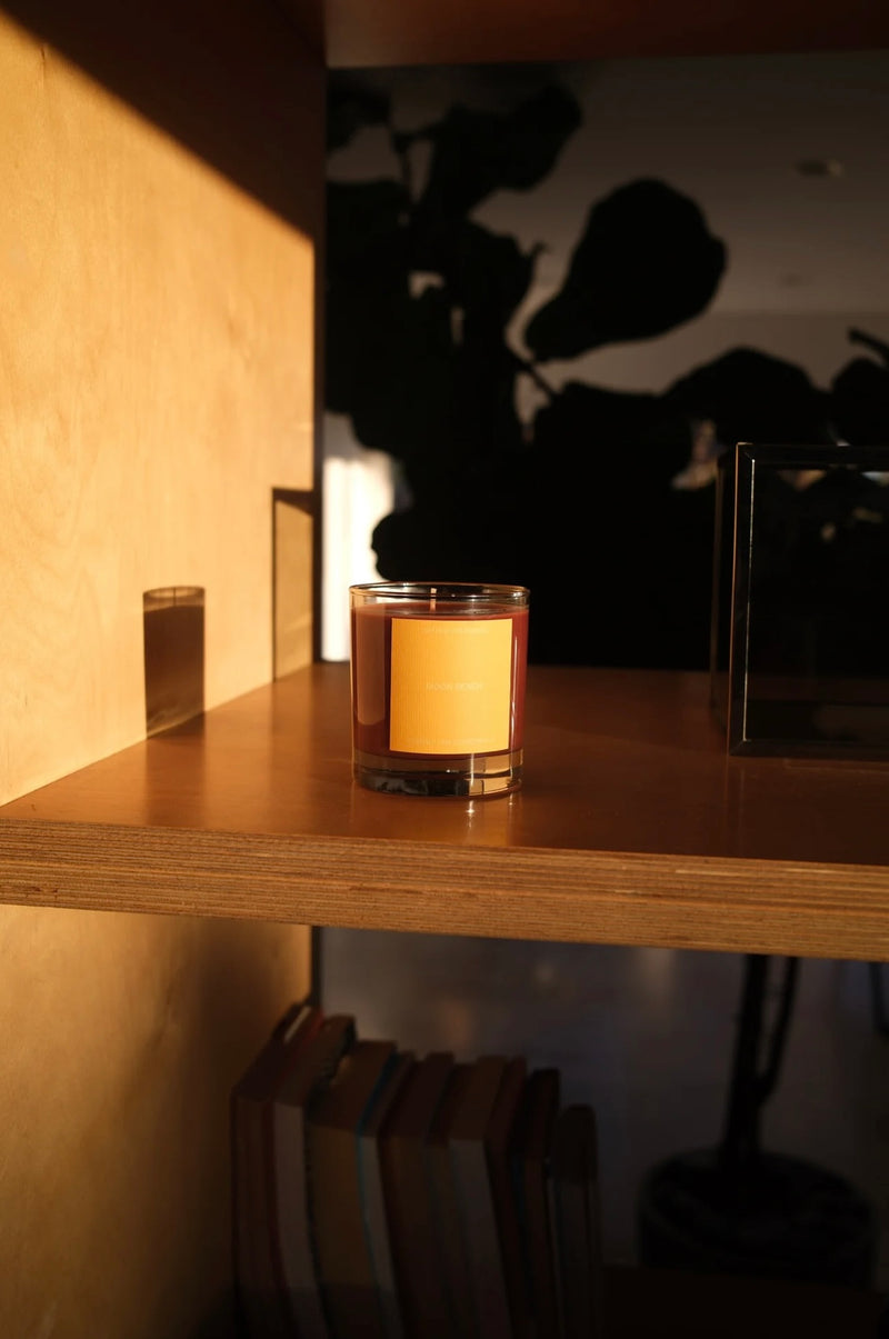 Candle in a glass holder on a wooden shelf with a blurred background