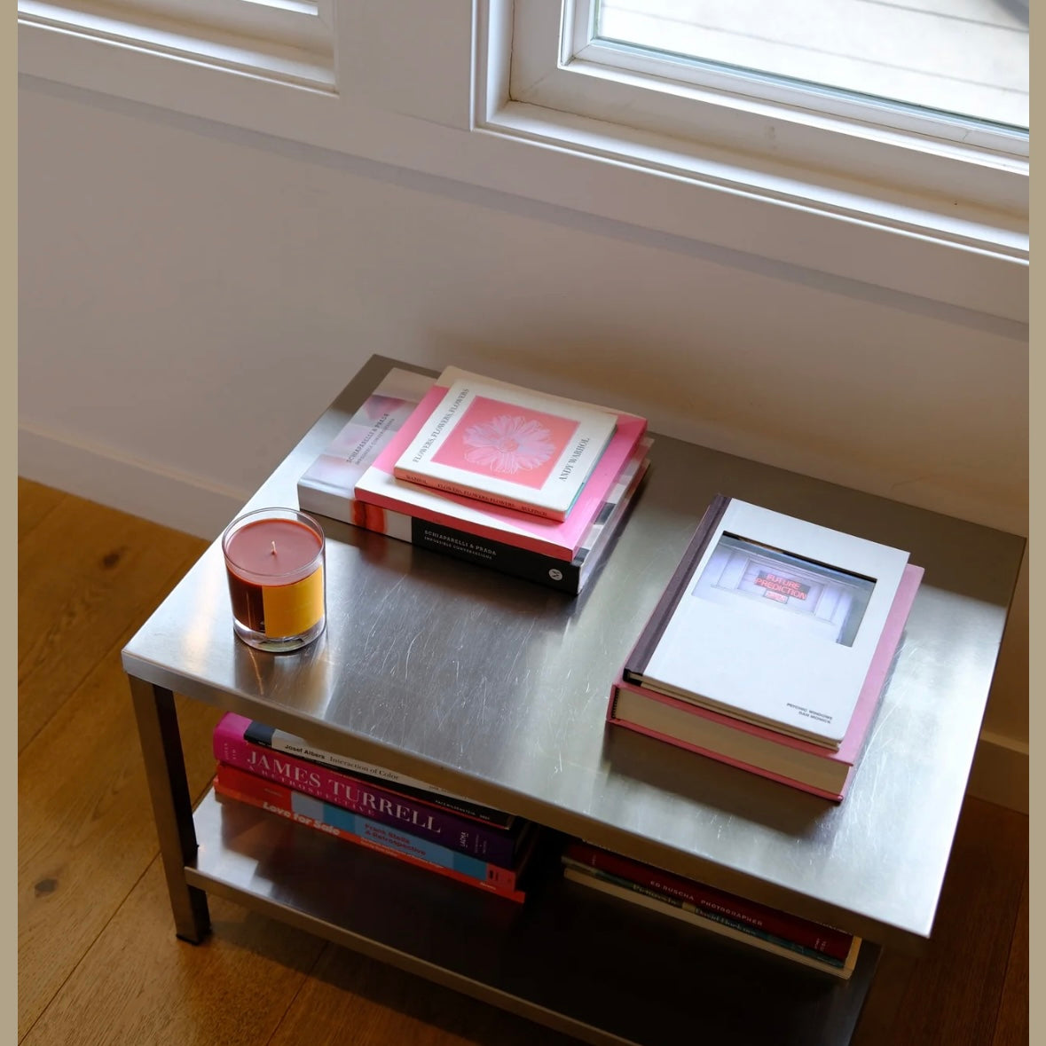 Small metal table with books and a candle in a softly lit room.