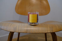 Glass jar candle with a yellow label on a wooden table
