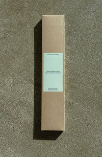 Brown cardboard box of incense sticks with a light green label on a textured gray surface