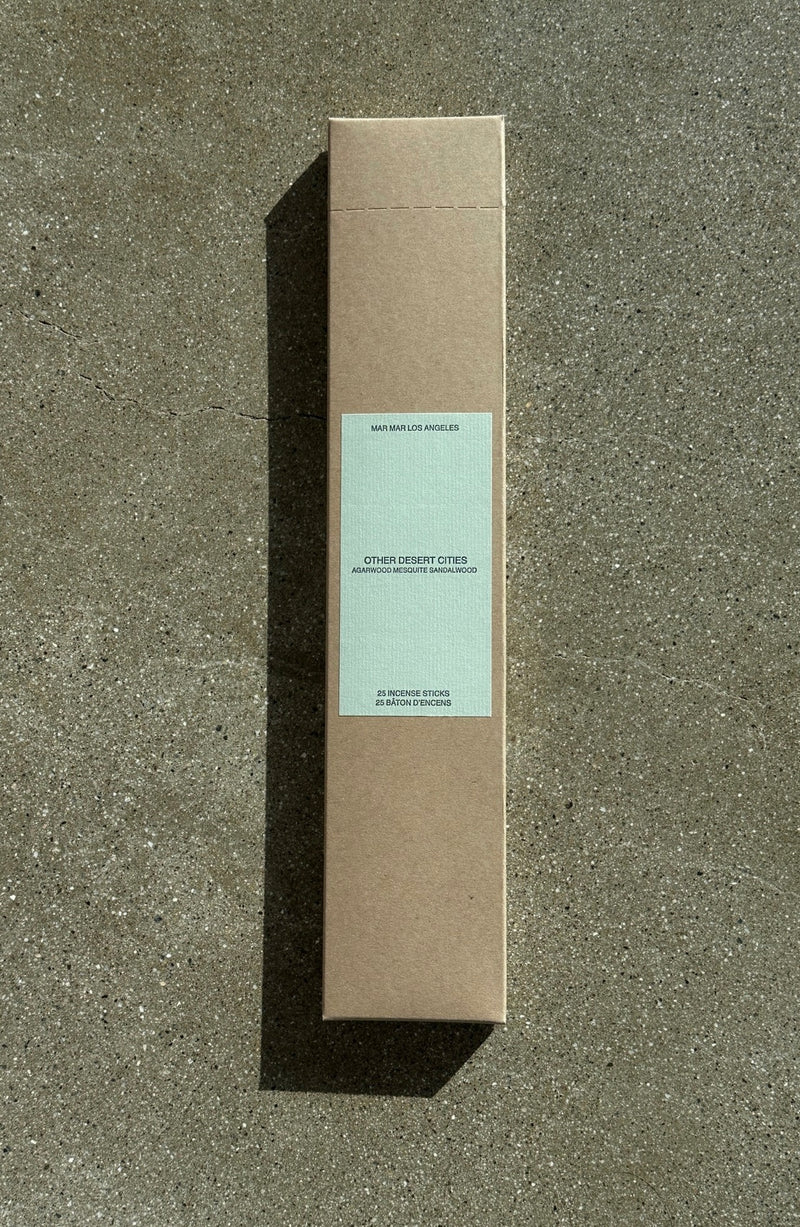 Brown cardboard box of incense sticks with a light green label on a textured gray surface