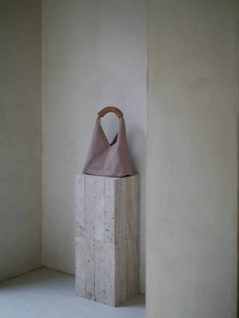 Purple handbag on a concrete block against a plain wall