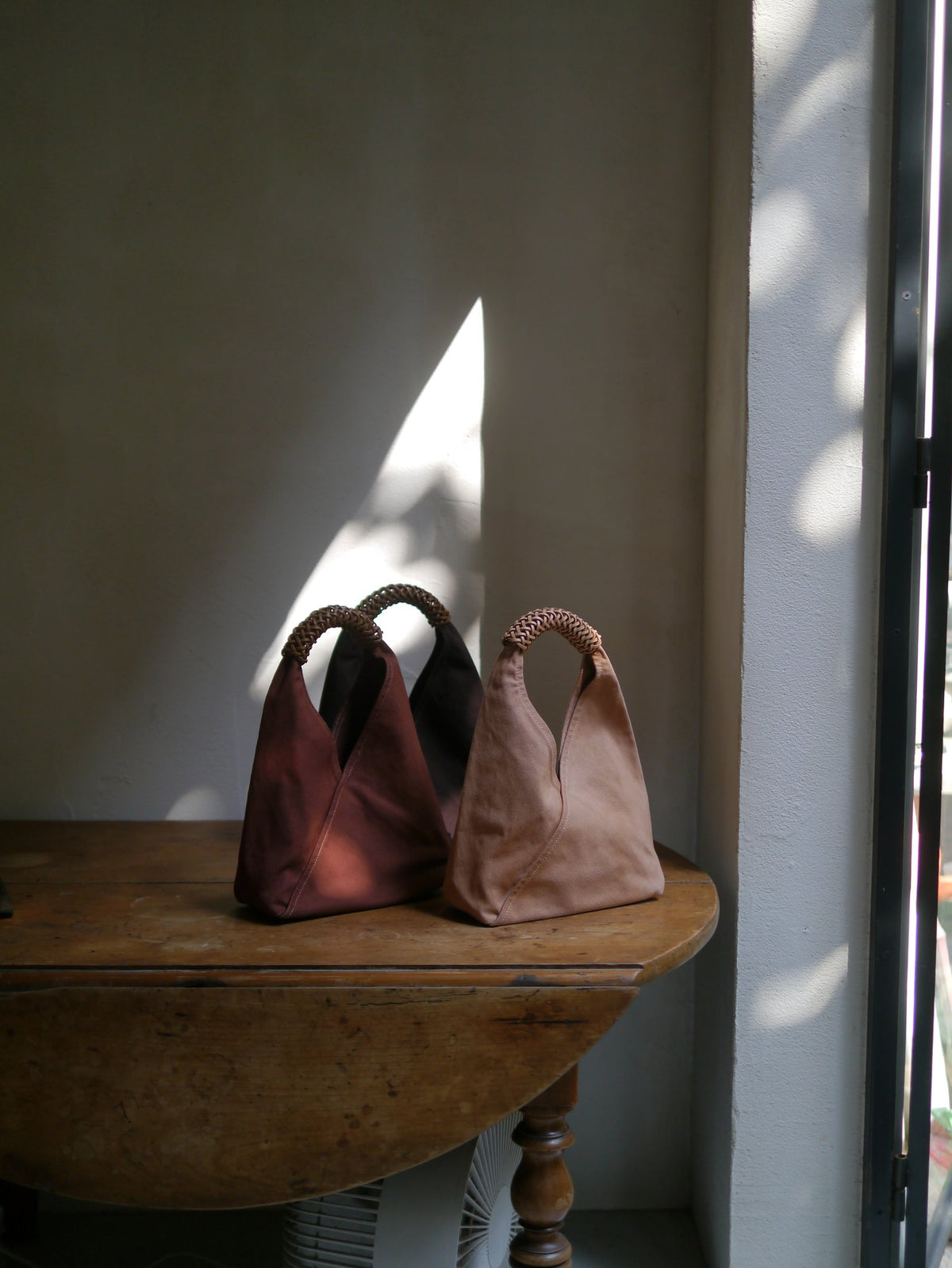 Three handbags on a wooden table with a neutral background