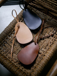 Three leather pouches in different colors on a woven surface