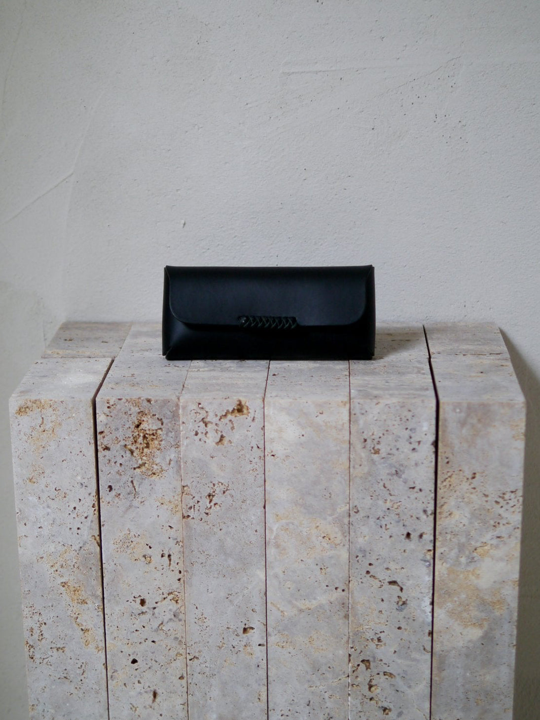 Black leather glasses case on a stone surface