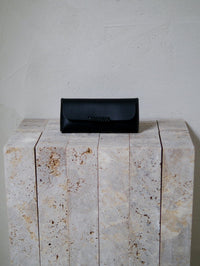 Black leather glasses case on a stone surface