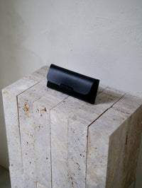 Black leather glasses case on a stone surface