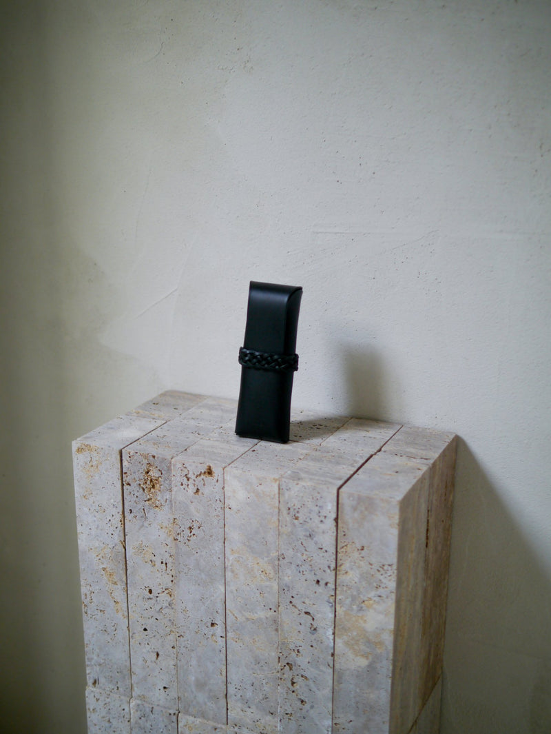 Black cylindrical object on a textured stone block against a plain wall