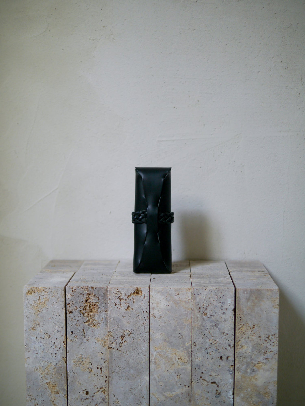 Black leather rectangular case on a textured stone surface with a plain background