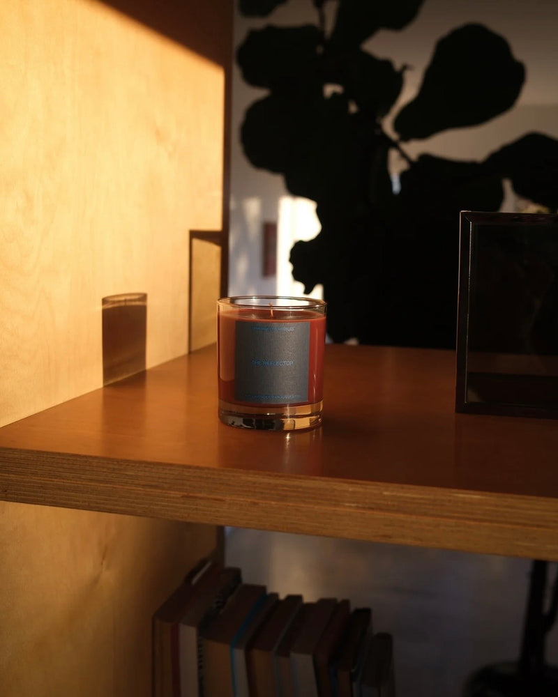 glass jar candle with a blue label on a bookshelf