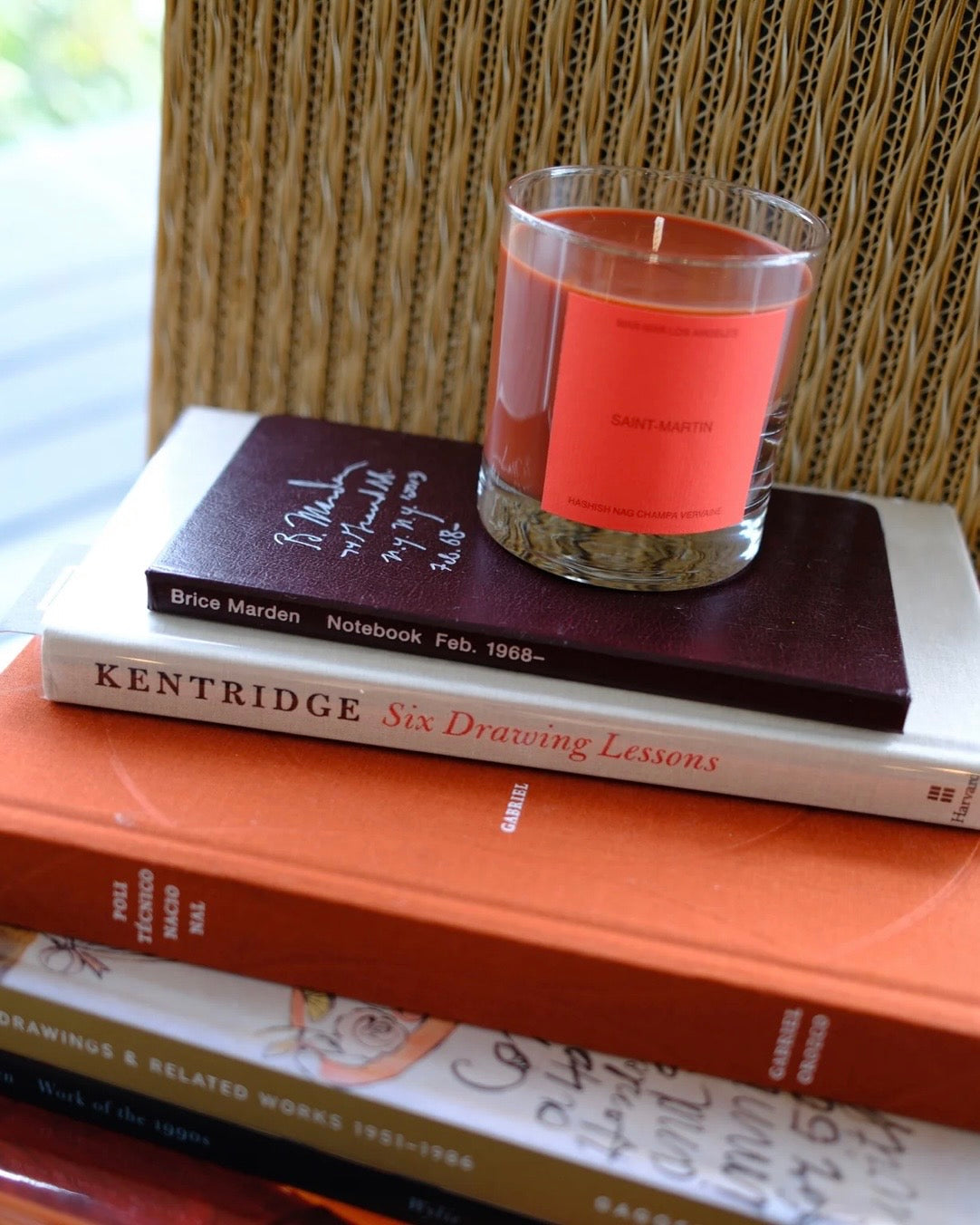 Stack of books with a candle on top, placed on a textured surface.