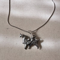 Silver pendant on a chain against a light background