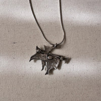 Silver necklace with a unique pendant on a light textured fabric background