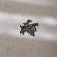 Back of a Silver brooch on a textured beige fabric background