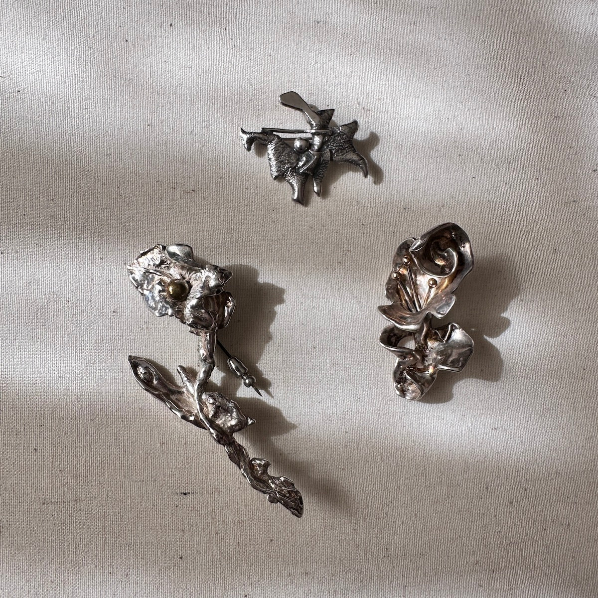Set of silver pendants and brooches on a textured beige surface
