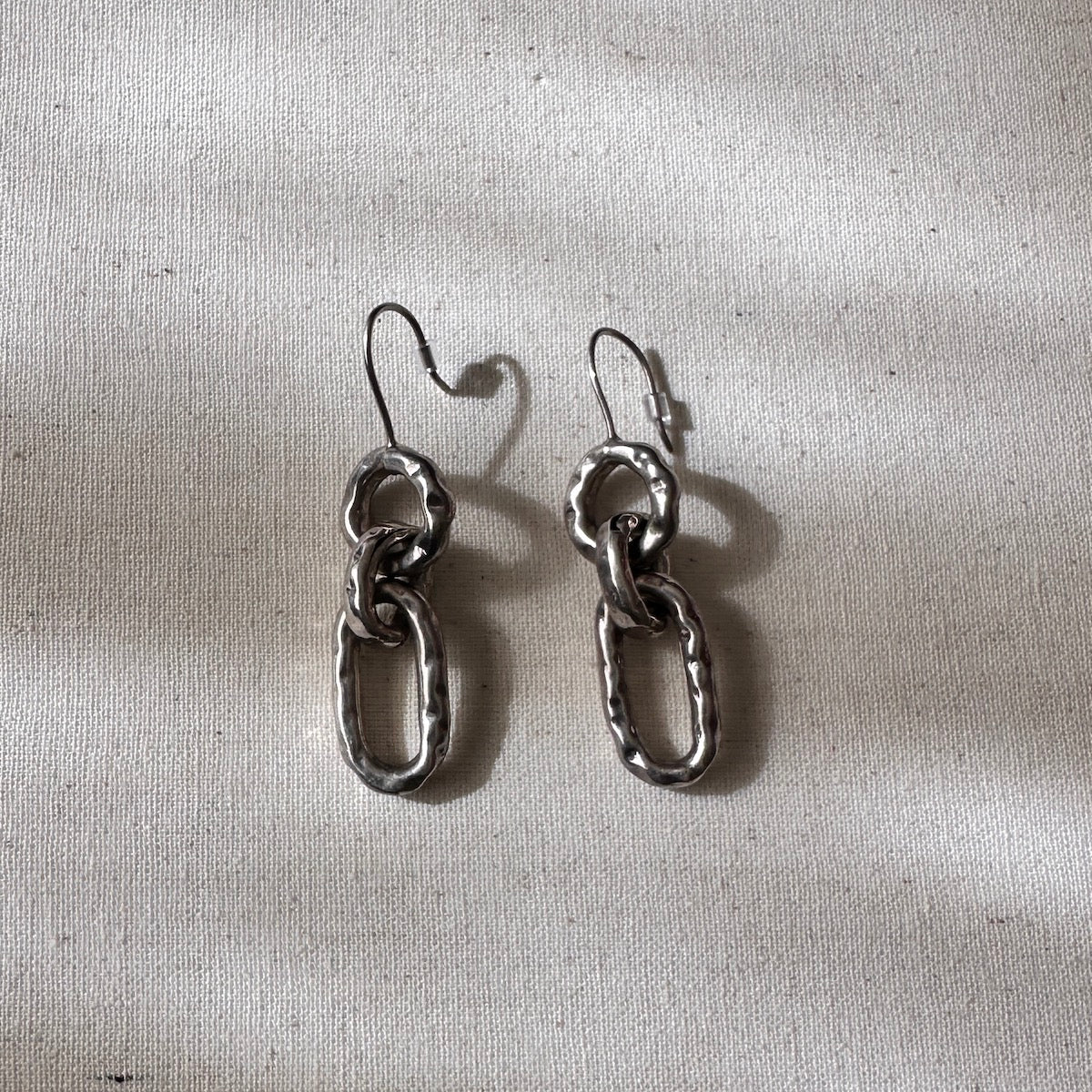 Pair of silver chain earrings on a textured gray background