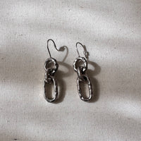 Pair of silver chain earrings on a textured gray background