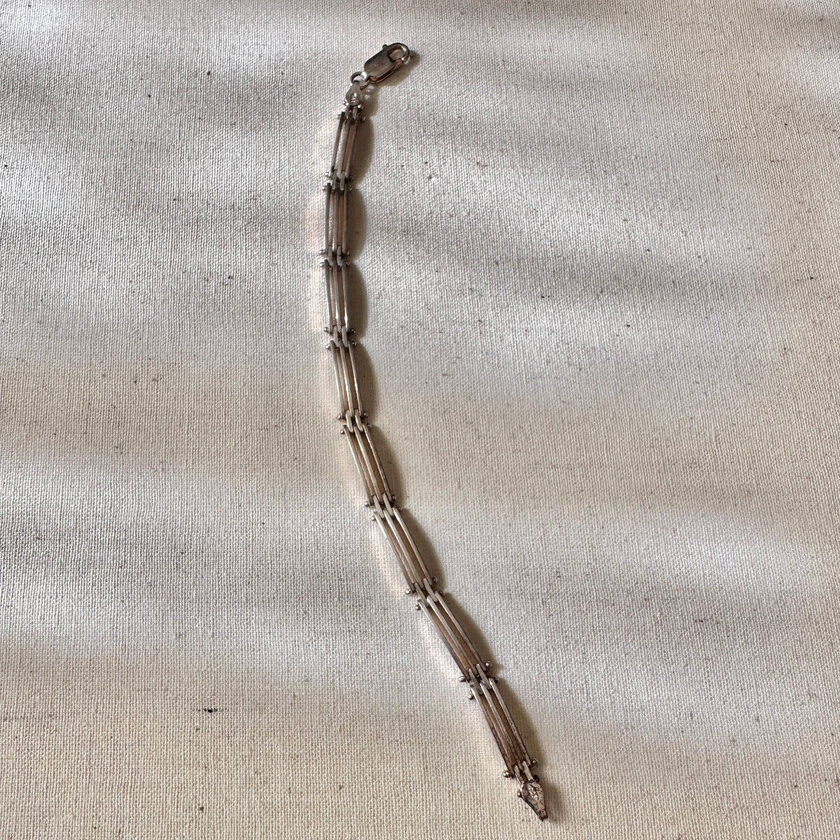 Silver bracelet on a textured beige fabric background