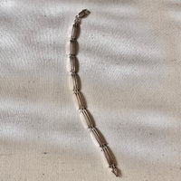 Silver bracelet on a textured beige fabric background