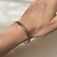 Silver bracelet on a wrist against a neutral background