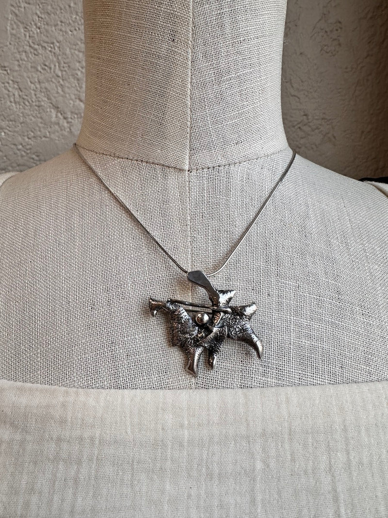 Silver necklace with a detailed pendant on a mannequin against a neutral background