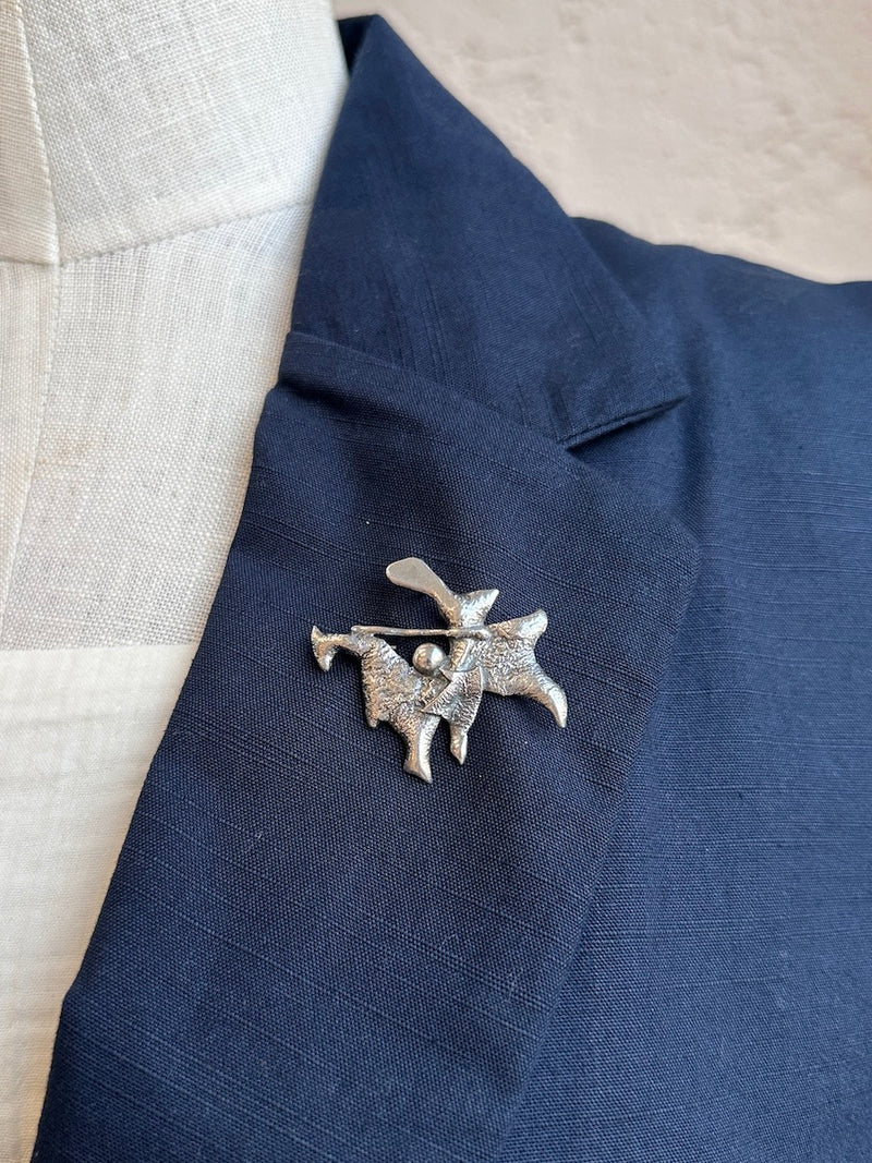 Silver brooch on a blue fabric jacket lapel