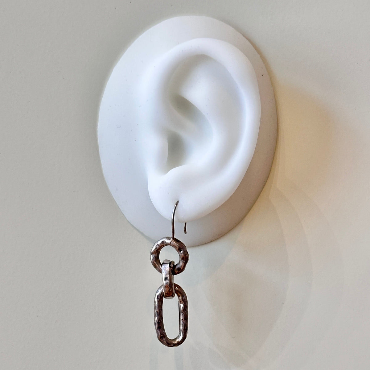 Earring with chain design worn on a white ear model