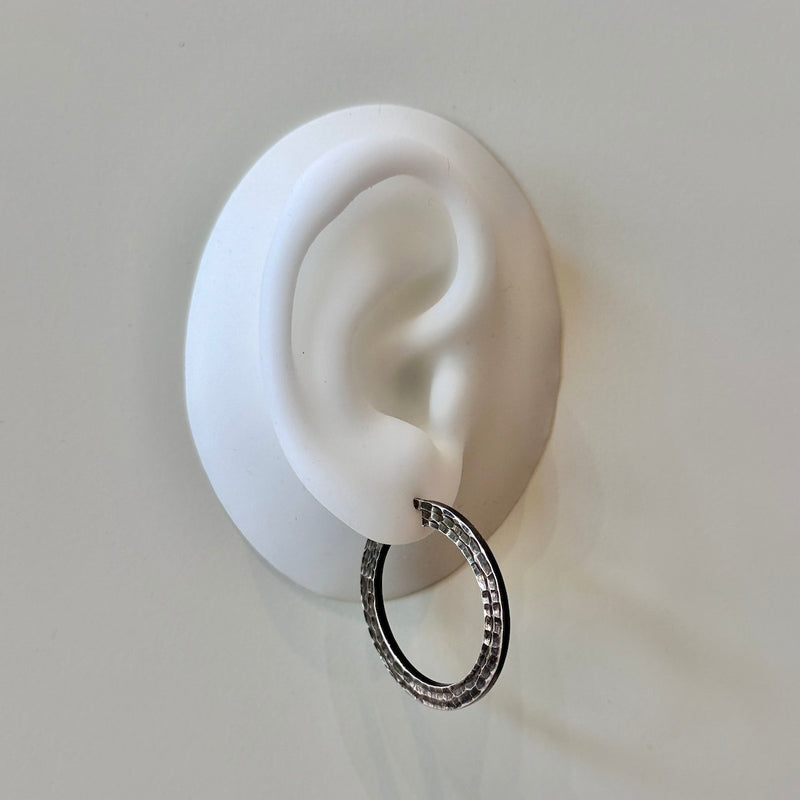 Silver hoop earring displayed on a white ear model against a light gray background