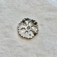 Silver floral-shaped brooch/pendant on a textured gray background