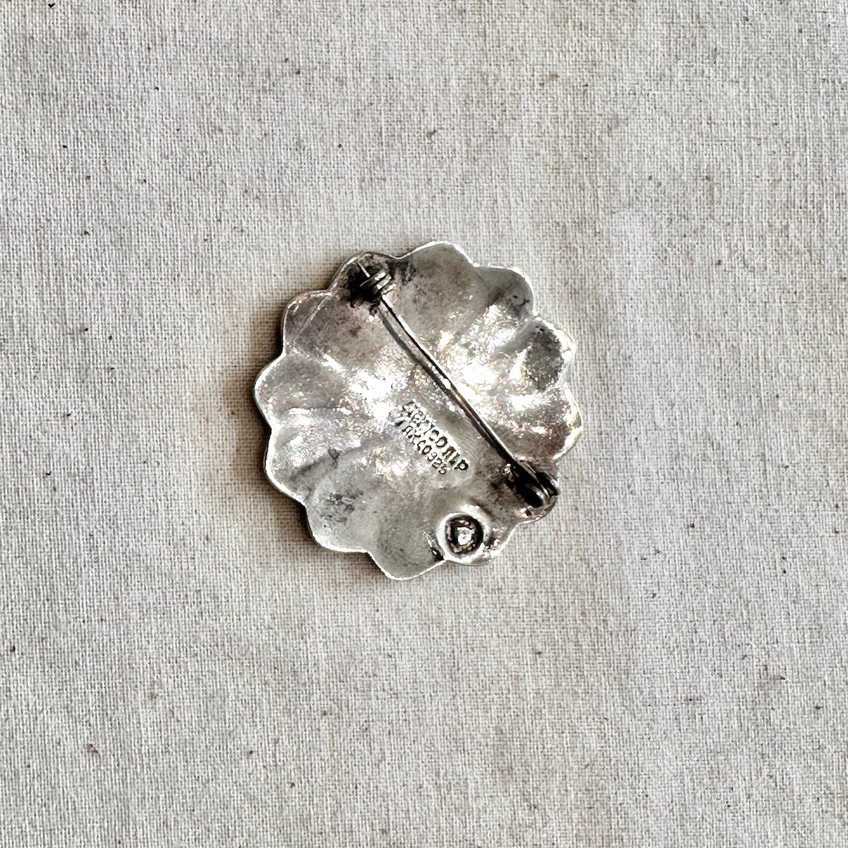 Silver brooch on a textured gray background