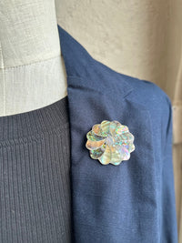Iridescent abalone brooch on a blue jacket lapel