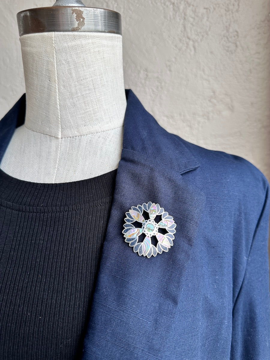 Floral brooch on a blue jacket lapel with a mannequin background