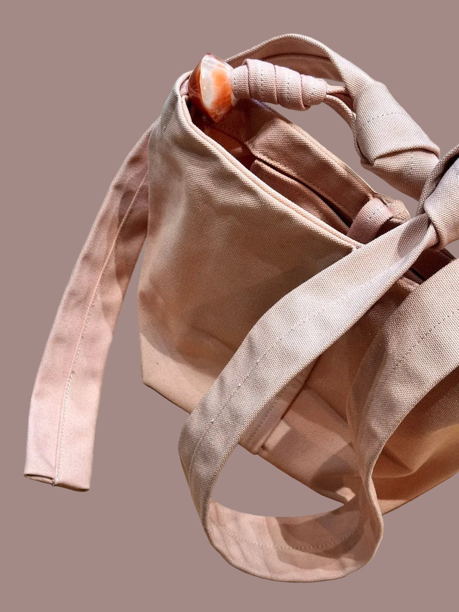 Pink canvas bag with jade bead, long strap, and inside pocket